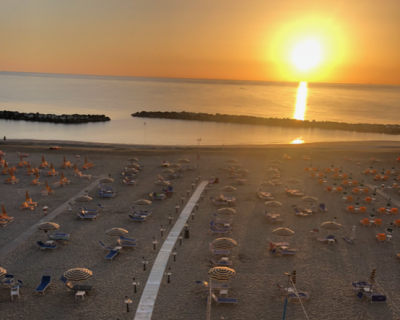 Spiaggia al tramonto con ombrelloni e mare calmo.